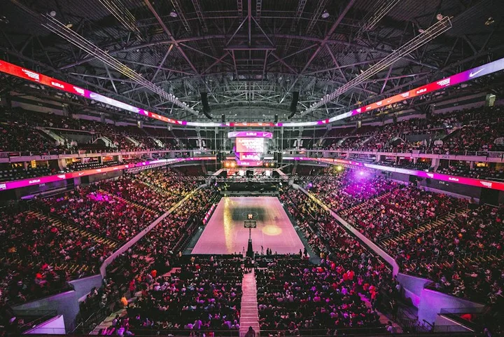 A basketball court surrounded by spectators in a brightly lit arena